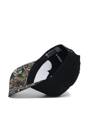 The Texas State Camo Hat - Trailblazer Edition by No Rivals features a camouflage brim and front, solid black cotton back, an adjustable snapback strap, and an interior label reading "NO RIVALS." The cap is shown sideways to highlight these details.