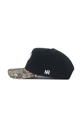 The No Rivals EWU Camo Hat - Trailblazer Edition is a black snapback with a structured fit, showcasing a camo-patterned brim and white embroidered “NR” lettering on the side.