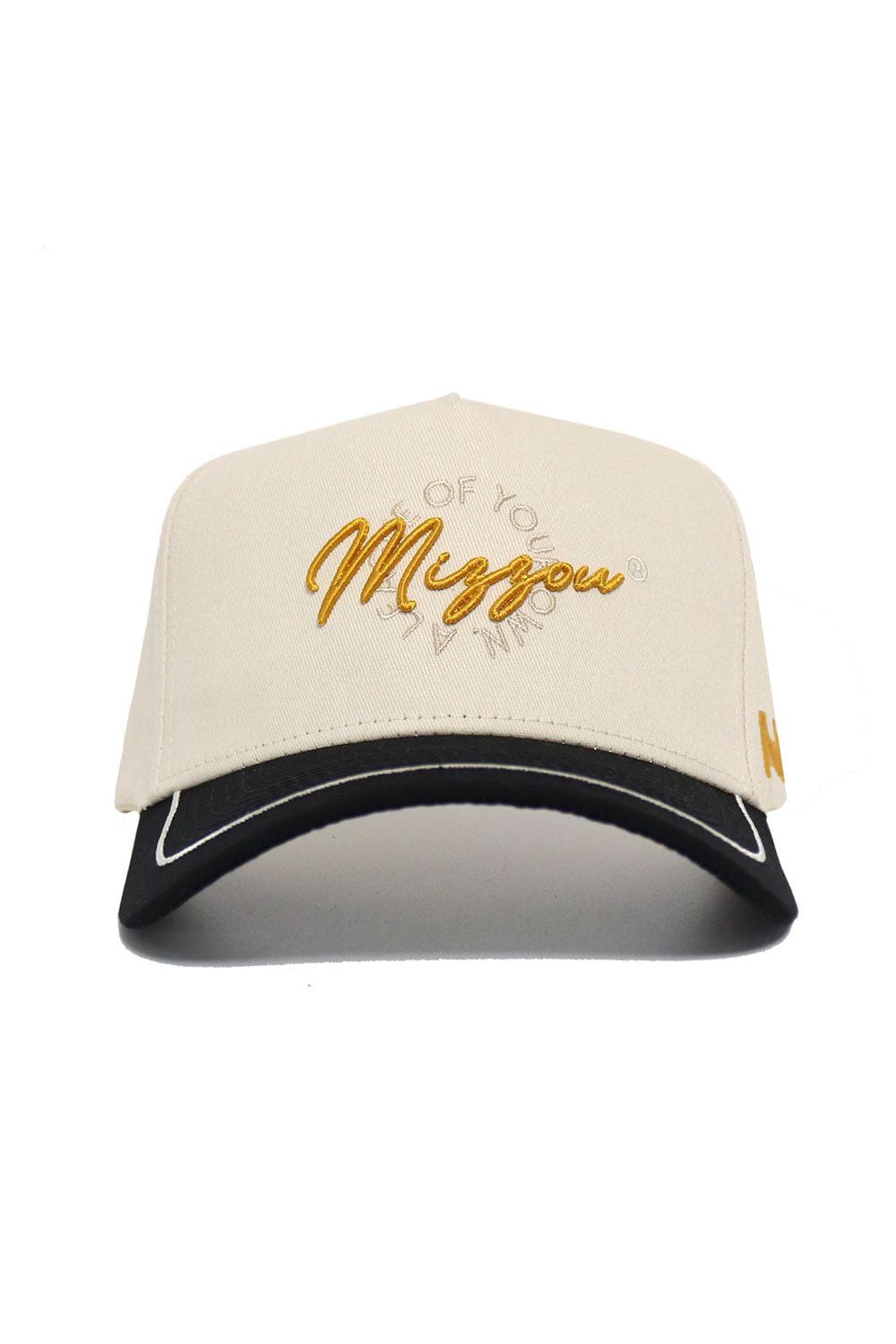 The Mizzou Tigers ALOYO Hat by No Rivals features “Mingou” embroidered in gold cursive, smaller surrounding text, a black brim with white outline, snapback adjustment, a gold side logo, and is made of high-quality beige cotton.