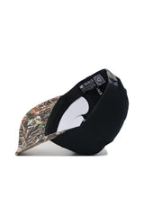 The No Rivals App State Camo Hat - Trailblazer Edition (B2B) is a black snapback cap with a camo-patterned brim, shown tilted to reveal its premium cotton interior, black band with white text, and a visible QR code.