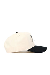 The No Rivals Wake Forest Triangle Game Cap Hat is a cream-colored cotton baseball cap with a black brim, structured fit, and a small black and white geometric logo on the front panel, shown in a side view.