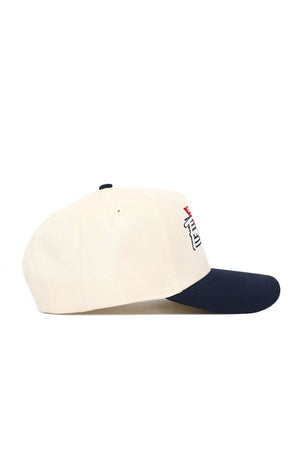 The Fresno State Triangle Game Cap Hat by No Rivals is a structured cream cap with a navy brim, side view shown. This officially licensed snapback features embroidered text and a small red front detail, partially visible.