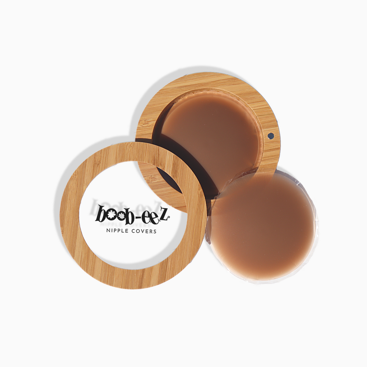 Product shot of Boob-eez Bamboo Compact with 6cm Dark tint Headlight Hiders inside and informative insert cards with wear and care instructions, close-up shot showing how to open and close the Bamboo Compact
