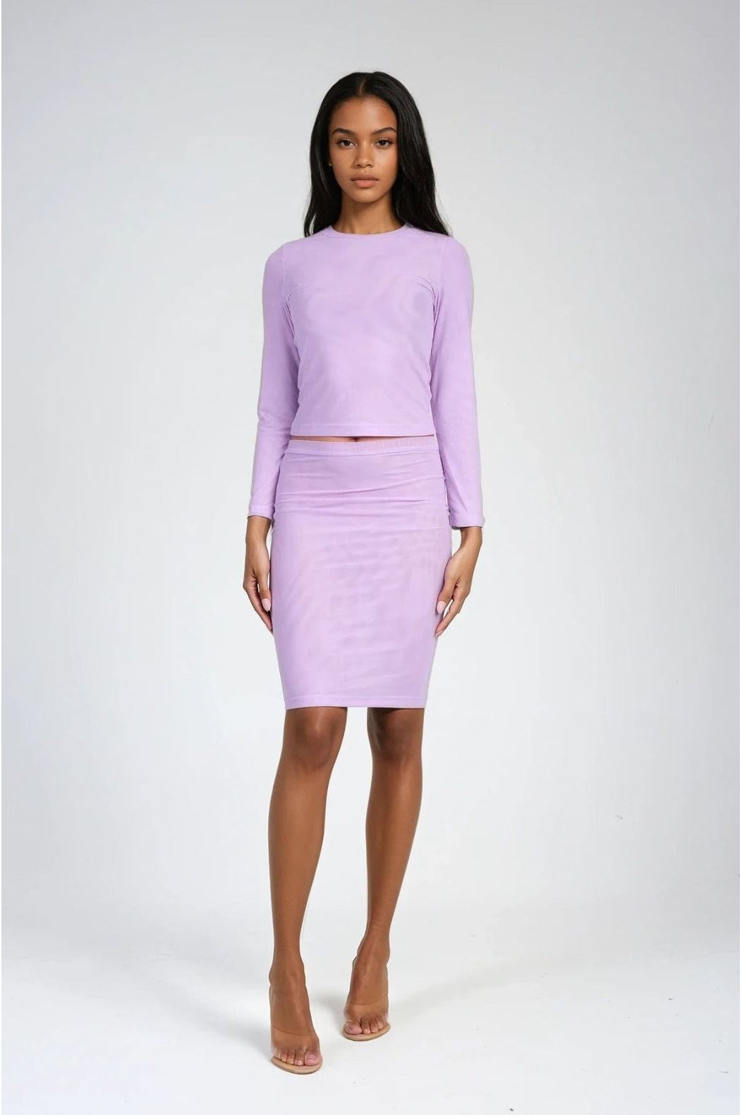 Woman wearing a matching lavender top and skirt set on a white background