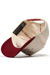The No Rivals Sports Club Pickleball Hat - Classic Red is shown inside out, displaying its label, inner lining with repeated NO RIVALS text, a QR code on the rim, a structured cream crown, and a maroon brim made from high-quality cotton.