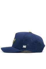 The No Rivals Athletic Pickleball Series Hat in navy features perforated side panels, a curved brim, yellow top button, white NR side patch, structured fit, and a front yellow embroidered badge partially visible from the side.