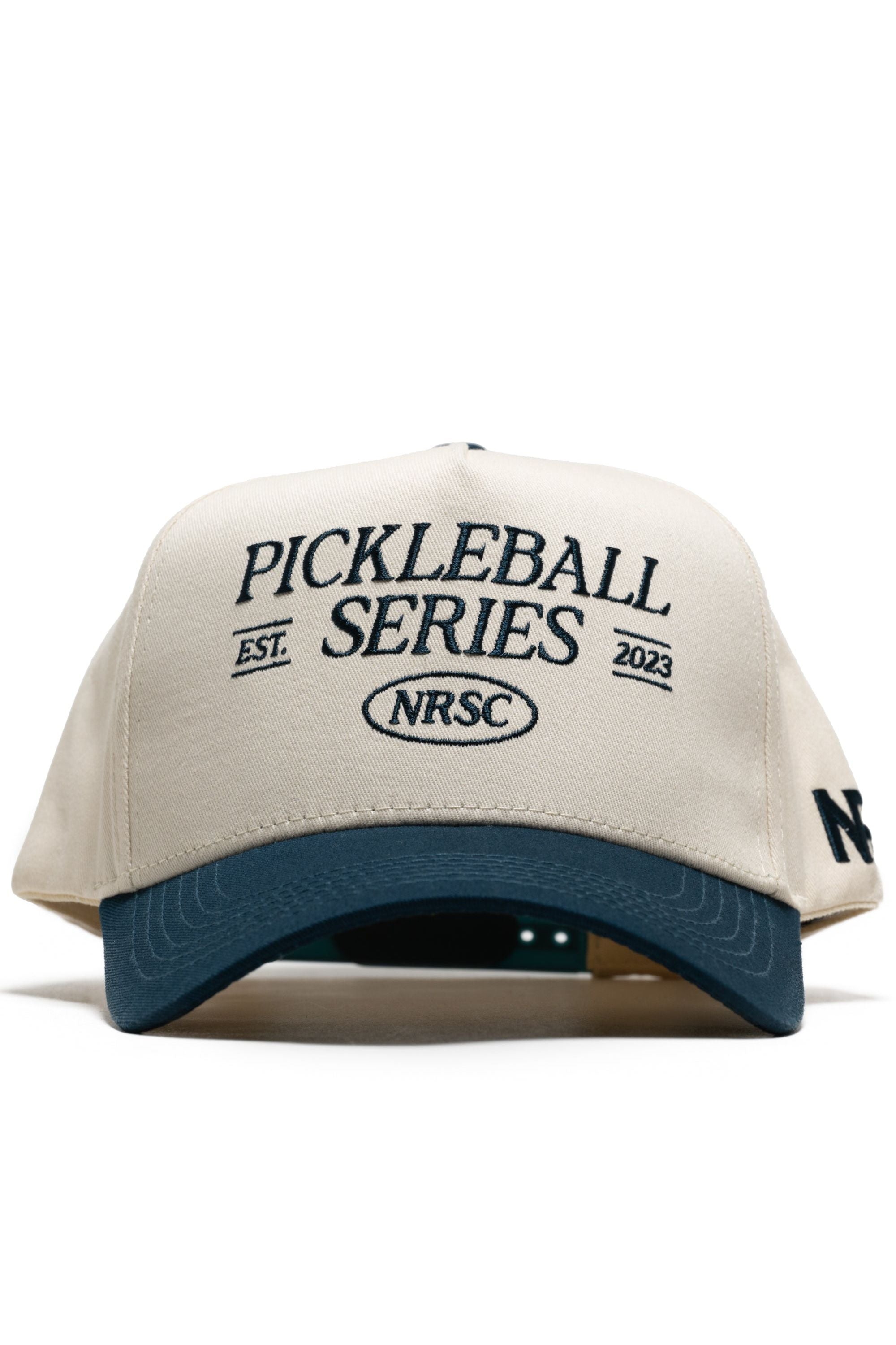 The Old School Pickleball Hat - Classic Blue by No Rivals is a beige and blue snapback with "PICKLEBALL SERIES EST. 2023 NRSC" on the front and "NR" on the brim, crafted from premium cotton for a structured fit.