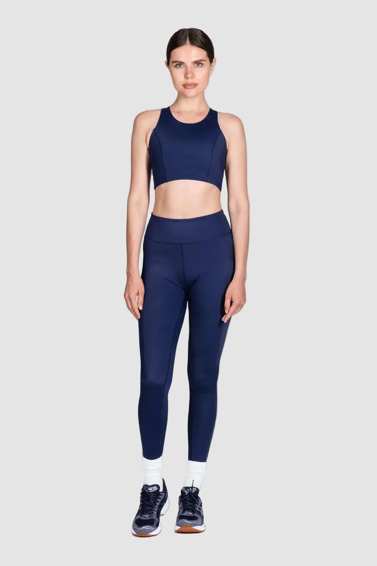 Woman wearing a navy blue athletic outfit on a white background