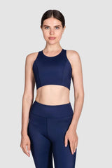 Woman wearing a navy blue sports bra and leggings on a white background
