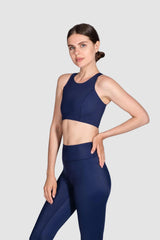Woman wearing a navy blue sports bra and leggings on a light gray background