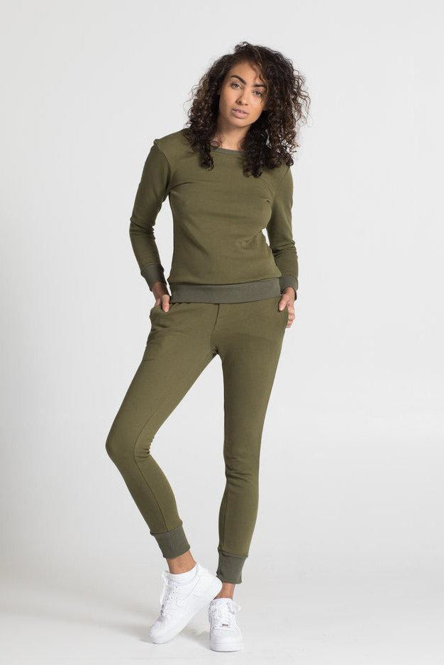 Woman wearing an olive green sweatshirt and pants on a white background