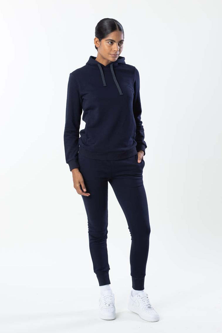 Woman wearing a navy tracksuit with white sneakers on a white background