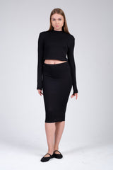 Woman wearing a black long-sleeve top and black pencil skirt on a white background