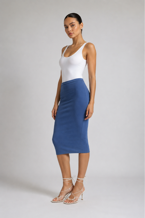 A woman modeling a color-blocked midi skirt with a white top, standing against a light gray studio background.