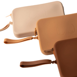 Product shot of durable Silicone Travel Cases for Silicone Stick-on Bra in Light Nude, Medium Nude, and Dark Nude, against a white background showing the Boob-eez branded detail and removable strap