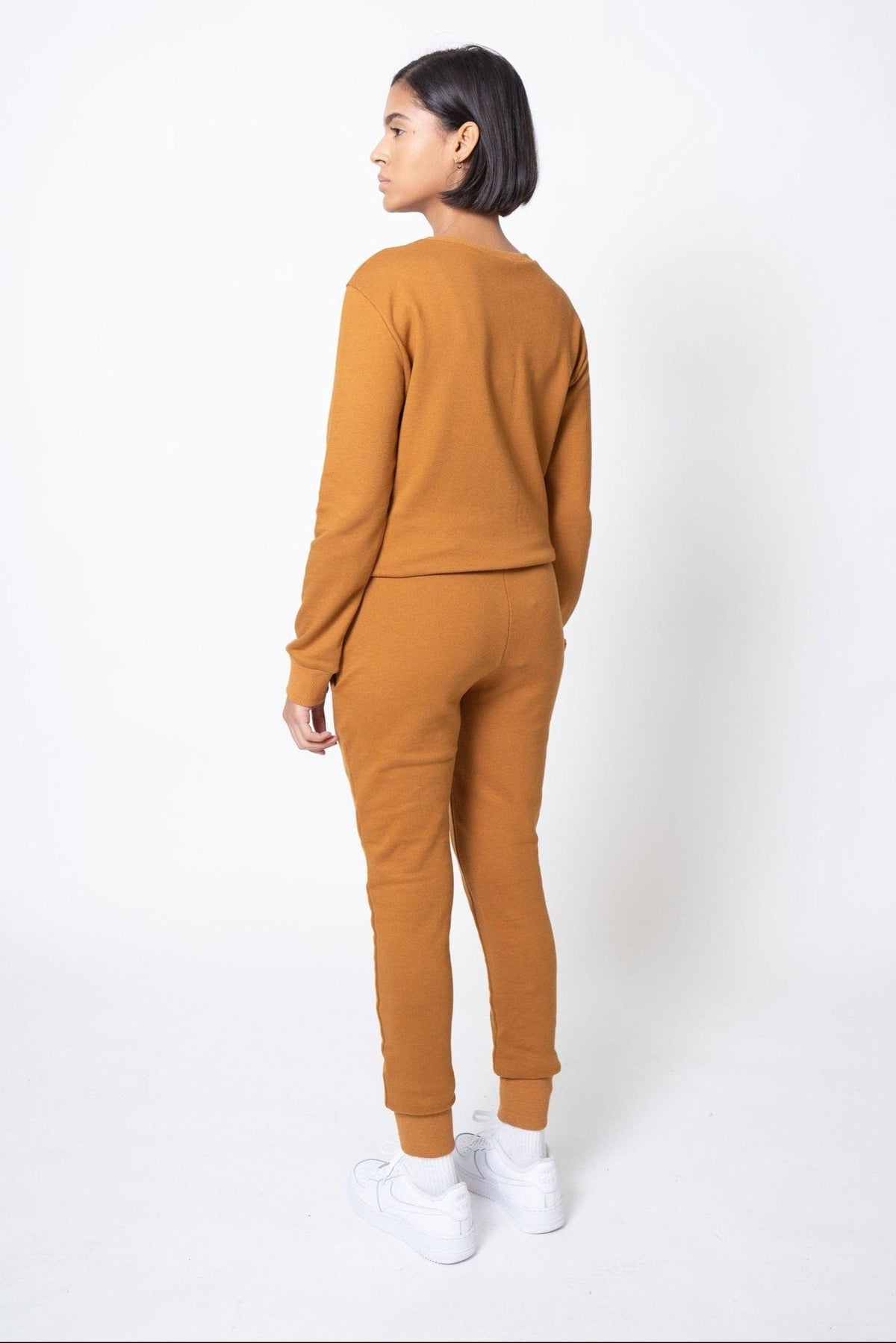 Back view of model wearing a mustard yellow outfit on a white background