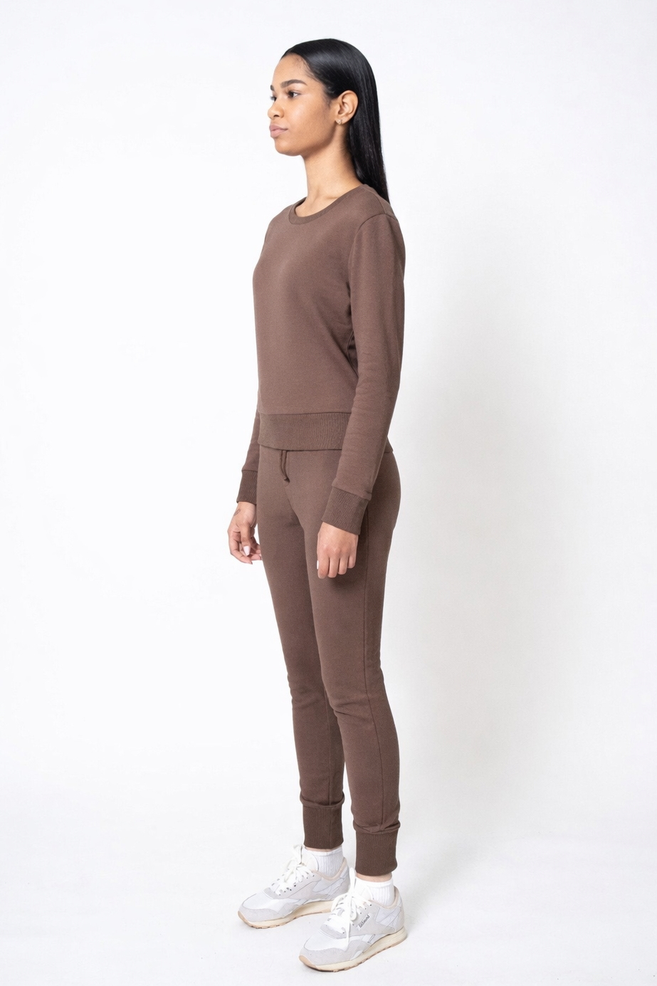 Woman wearing a brown outfit standing against a white background
