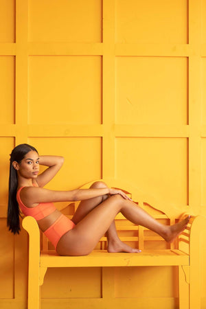 Women laying in chair with bikini set against a yellow background