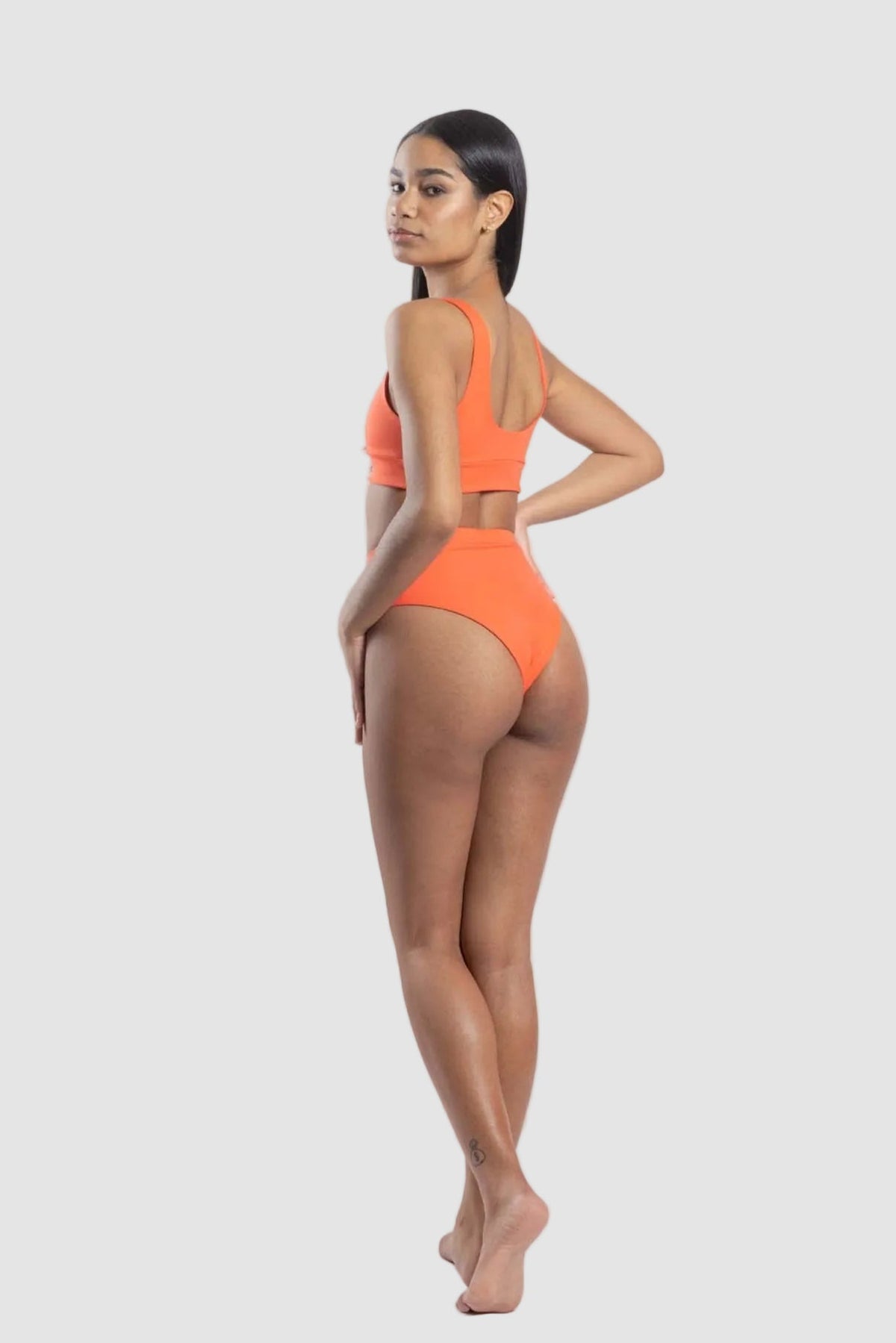 Woman wearing an orange bikini set on a white background