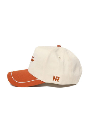 The Austin ALOYO Hat by No Rivals is a beige structured snapback with an orange brim, top button, and stitching. Made from high quality cotton, it features "NR" embroidered in orange above the brim.