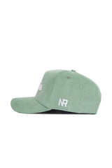 The No Rivals Dallas Corduroy Hat from the Spring Showers Collection is shown in side view, featuring a vibrant spring green color, white embroidered "NR" lettering on the side, and a top button. This structured cap offers an adjustable fit for enhanced comfort and style.