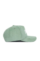 The Dallas Corduroy Hat by No Rivals, from the Spring Showers Collection, is a structured snapback cap in spring green corduroy with a curved brim, shown in profile. It features white embroidered text on the front, ventilation eyelets on the crown, and offers a stylish, comfortable fit.