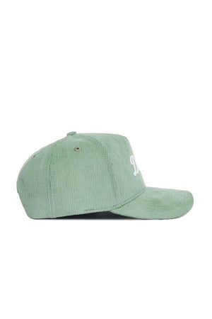 The Dallas Corduroy Hat by No Rivals, from the Spring Showers Collection, is a structured snapback cap in spring green corduroy with a curved brim, shown in profile. It features white embroidered text on the front, ventilation eyelets on the crown, and offers a stylish, comfortable fit.