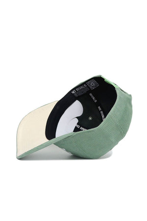 The Dallas Corduroy Hat - Structured in Spring Green from the No Rivals Spring Showers Collection is displayed upside down, showcasing its cream-colored brim and black inner lining repeatedly printed with "NO RIVALS" in white lettering. This adjustable hat offers a structured fit for lasting style and comfort.