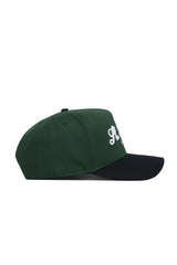 The No Rivals St.Pattys Shamrock Hat is a green corduroy cap with a black brim, shown from the side. Partially visible white embroidered text appears on the front. Unstructured fit offers casual comfort.