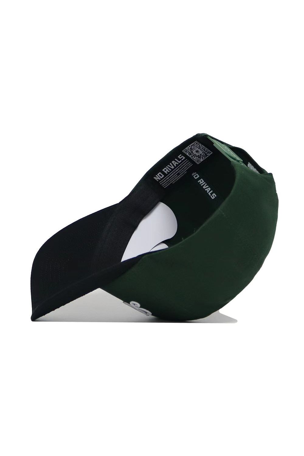 The St.Pattys Shamrock Hat by No Rivals is a green corduroy, unstructured fit cap. Turned upside down, it reveals a black interior with “NO RIVALS” in white and a QR code on the inner band. The brim’s underside is dark.