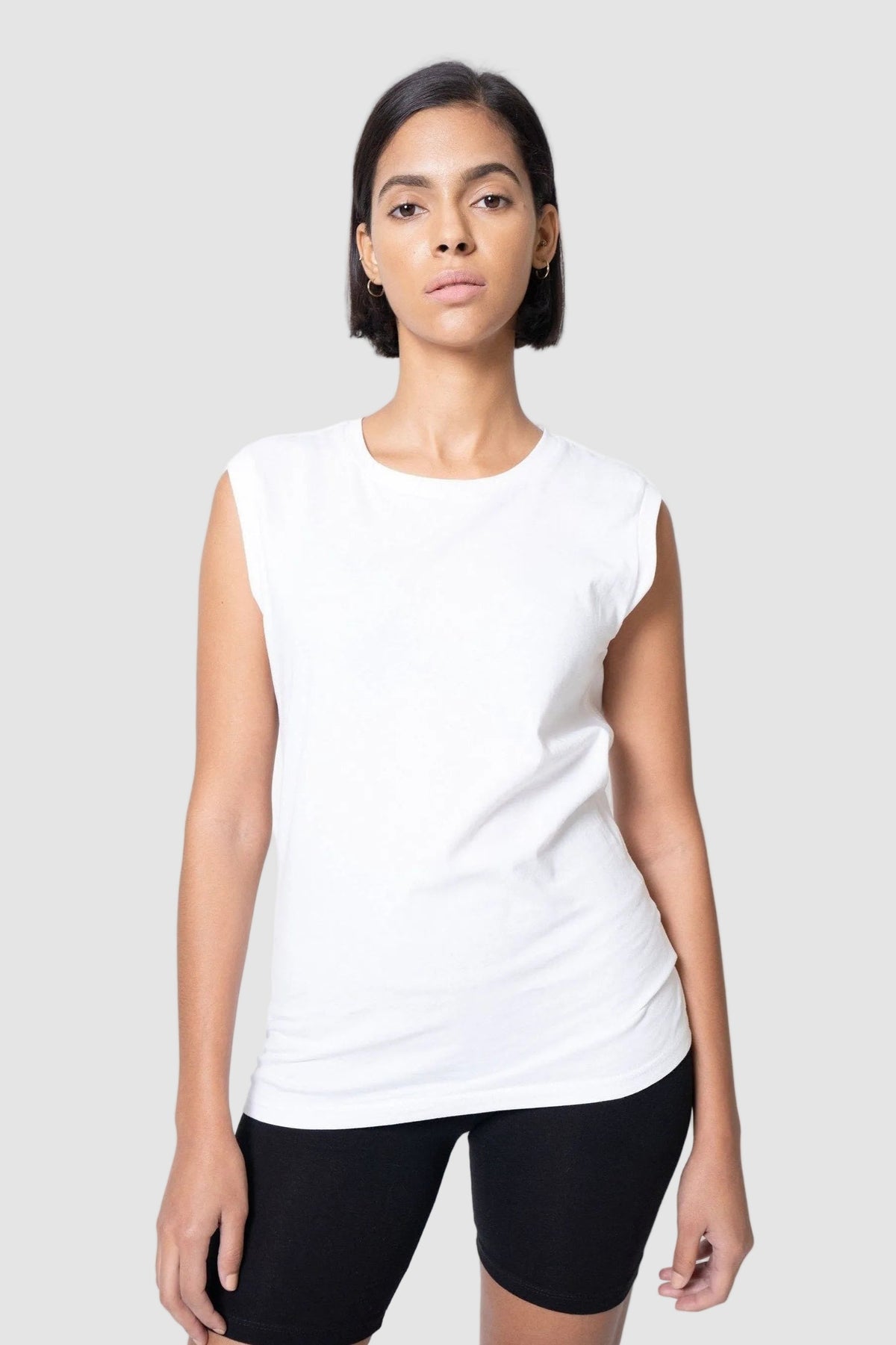 Woman wearing a white sleeveless top and black shorts on a light gray background