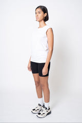 Person wearing a white sleeveless top, black shorts, and white sneakers on a white background