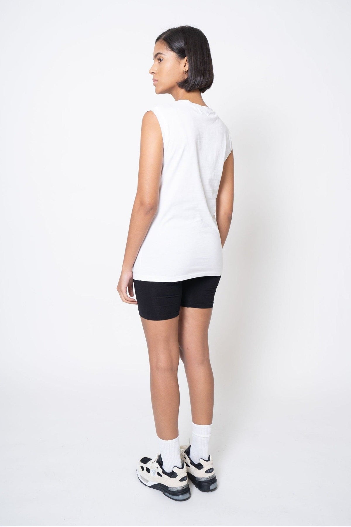 Person wearing a white sleeveless top and black shorts on a white background