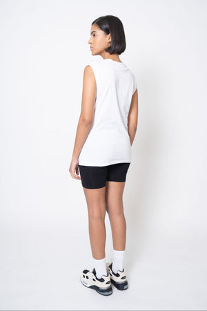 Person wearing a white sleeveless top and black shorts on a white background