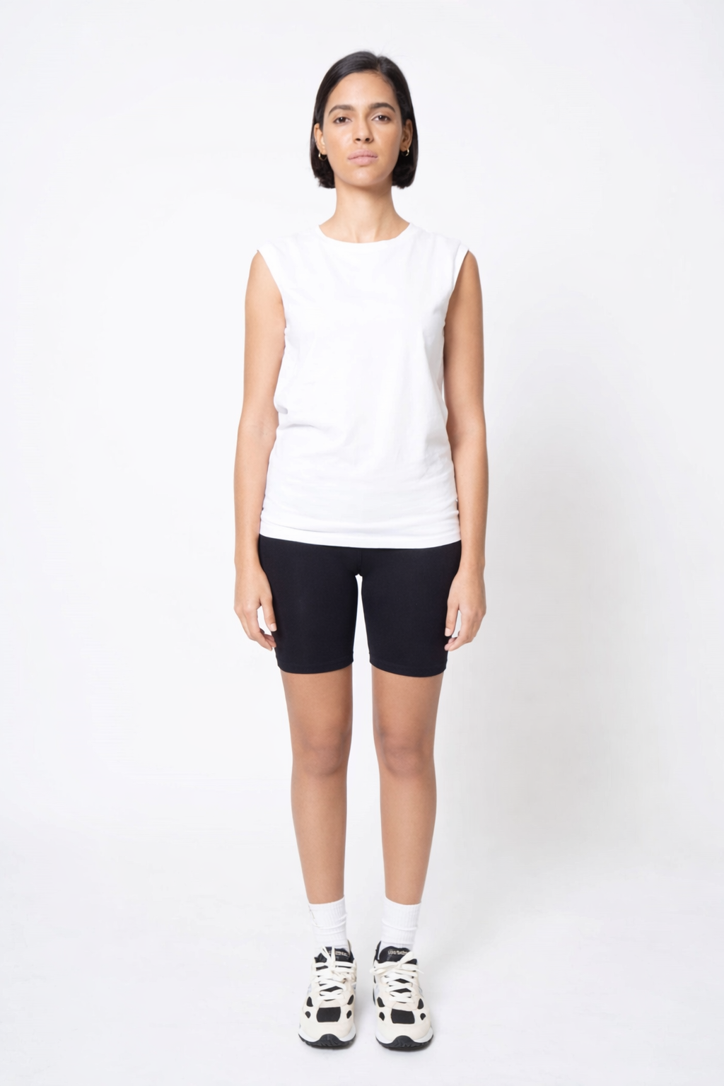 Person wearing a white sleeveless top and black shorts on a white background