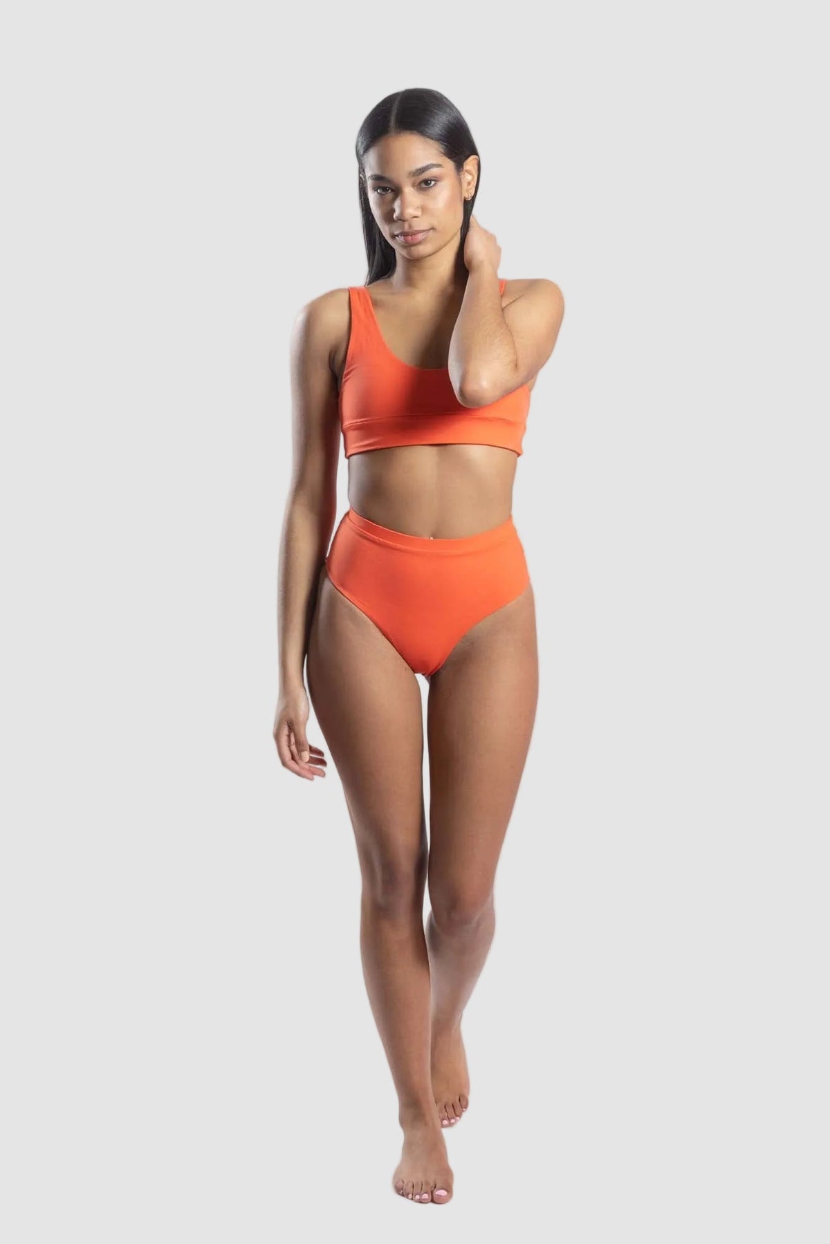Woman wearing an orange bikini set on a white background
