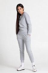 Woman wearing a grey sweatshirt and sweatpant on a white background
