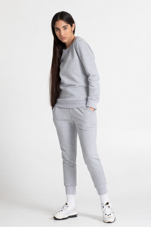 Woman wearing a grey sweatshirt and sweatpant on a white background