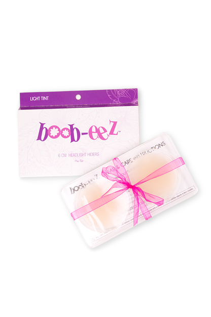 Product shot of reusable Light tint Headlight Hiders size 6cm in recycled craft packaging, including information insert card with wear and care instructions and brand story, close-up shot, against a white background