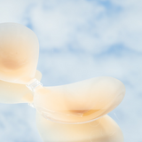 Product shot of reusable and sticky Silicone Stick-on Bra laying flat against mirrored sky background, close-up side shot of the Silicone Stick-on Bra showing the razor thin edges 