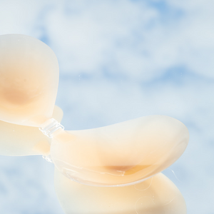Product shot of reusable and sticky Silicone Stick-on Bra laying flat against mirrored sky background, close-up side shot of the Silicone Stick-on Bra showing the razor thin edges 